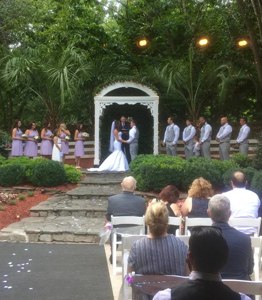 Ceremony at the garden arch with the bridal party in lavender