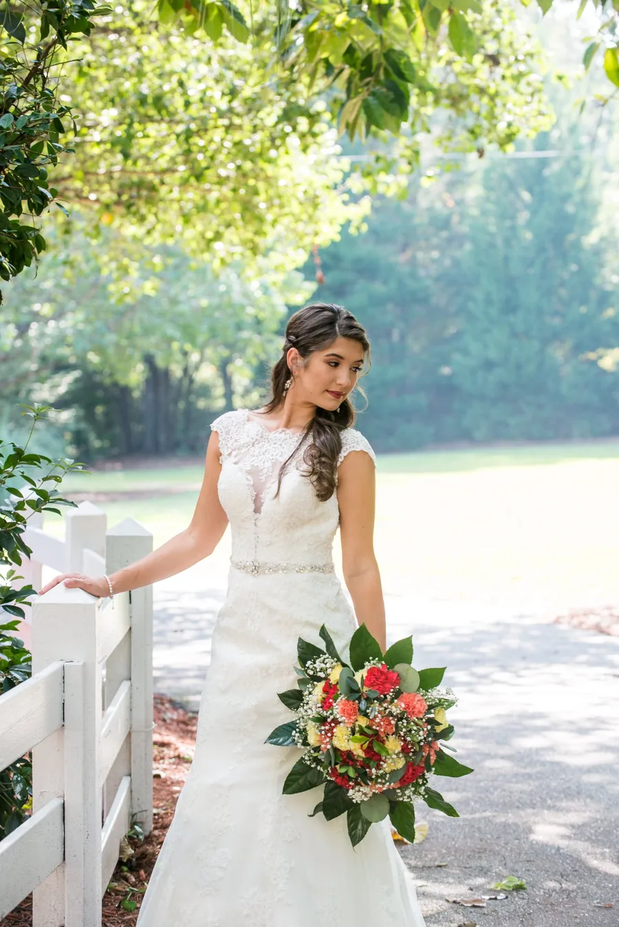 Bride with her bouquet along the white fence