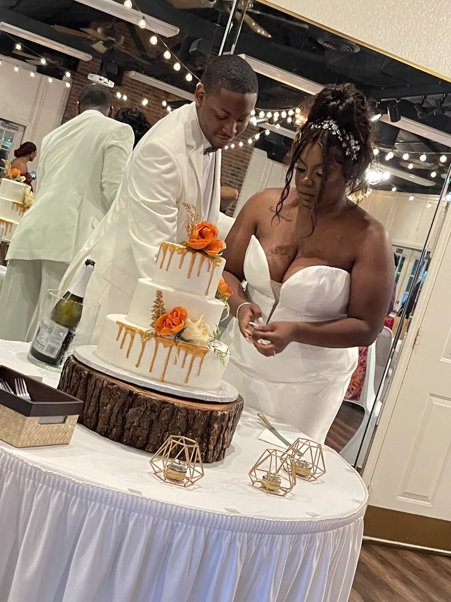 A couple cutting their caramel drip wedding cake