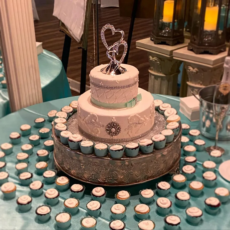 Round wedding cake ringed with matching cupcakes