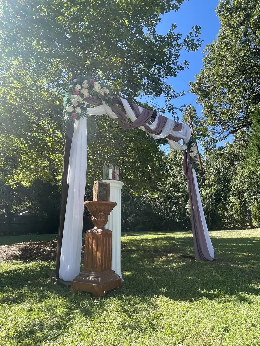 A draped ceremony arbor beneath the trees