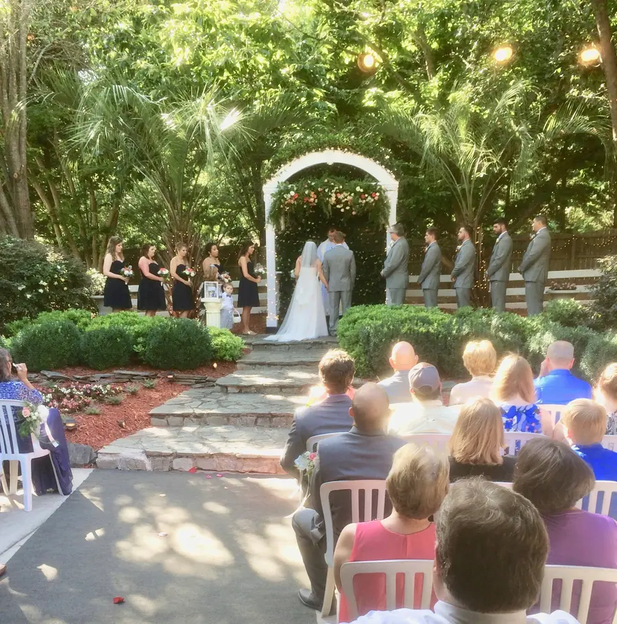 Wedding guests gathered at the greenery-covered garden arch