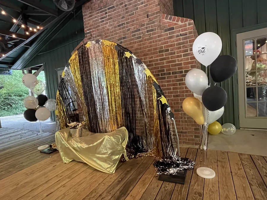Gold fringe photo backdrop with balloons at a graduation party
