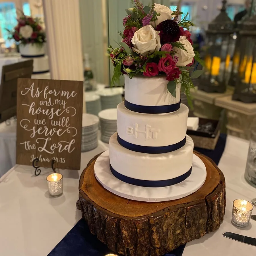 Navy ribbon wedding cake on a wood slice stand