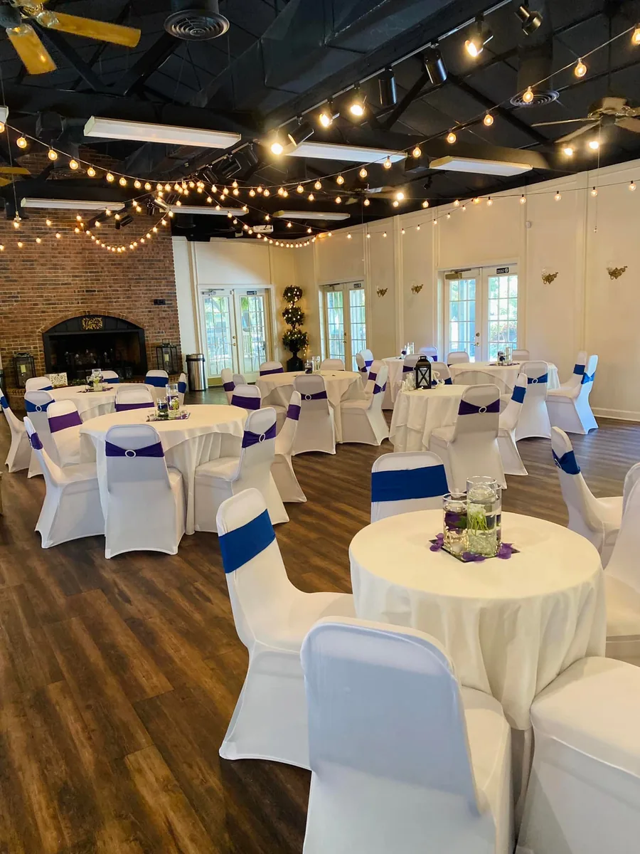 Round tables with white chair covers and blue sashes