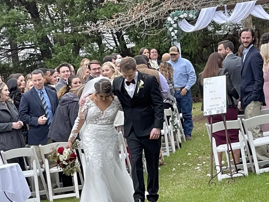 The newlyweds walking back up the garden aisle