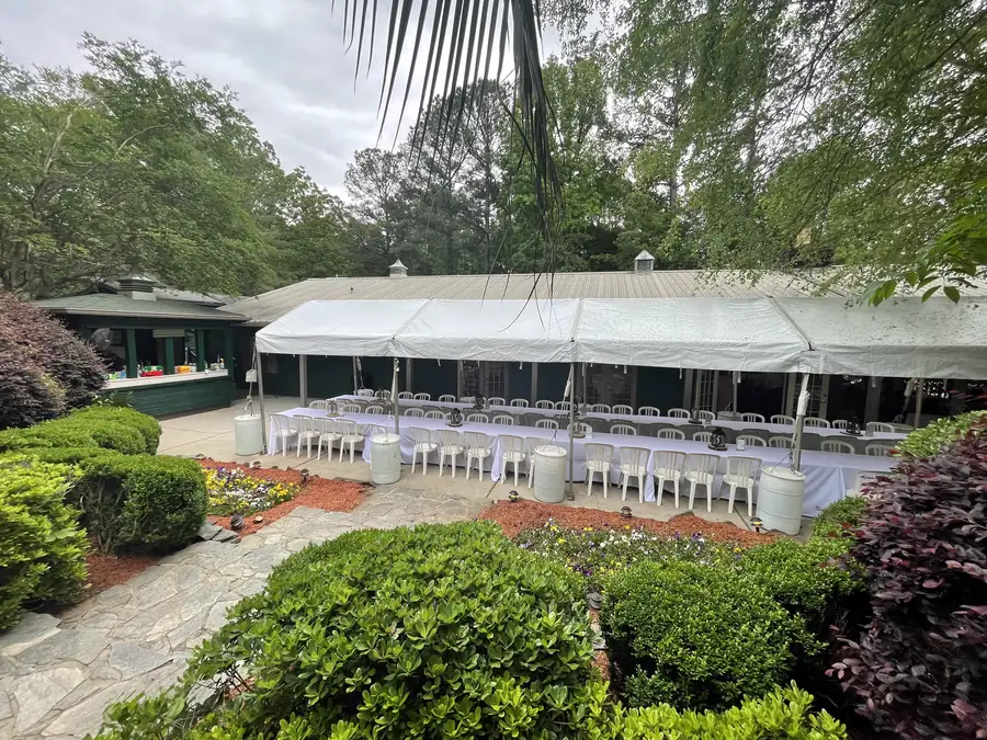 A tented reception set on the lawn beside the gardens